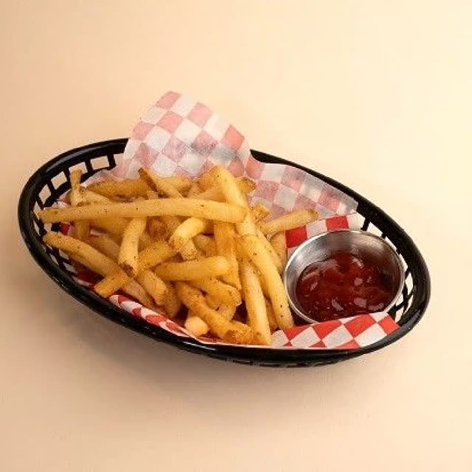 A black basket of golden french fries with a side of ketchup on a checkered paper liner.