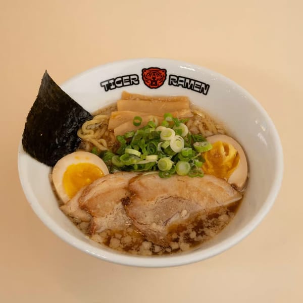 A bowl of Tiger Ramen with pork, soft-boiled eggs, bamboo shoots, green onions, and nori.