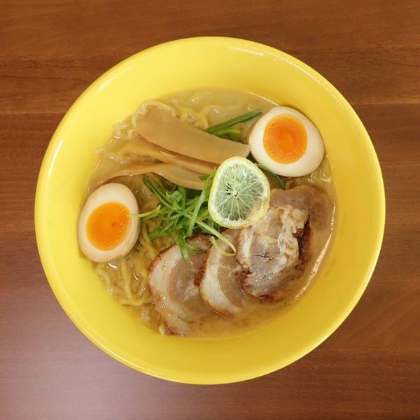 Tiger Ramen's ramen bowl with pork, soft-boiled eggs, bamboo shoots, green onions, and a lemon slice.